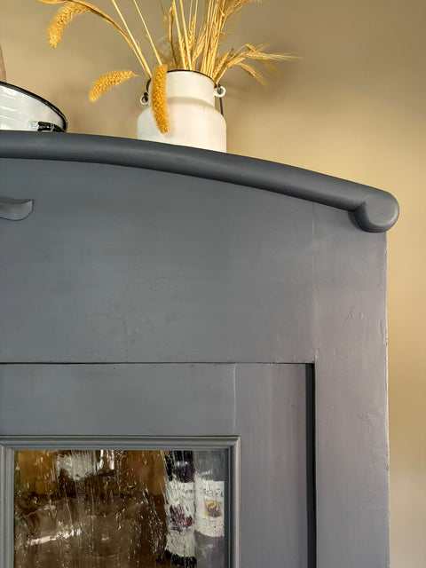 Zweitürige antike Weichholzvitrine in Kreidefarbe Smoke, grau-blau, mit eleganten Holzdetails und antikem Design.