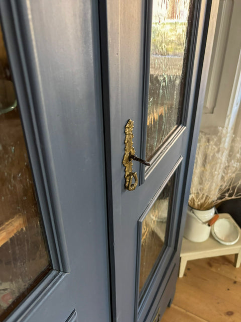 Zweitürige antike Weichholzmöbel Vitrine in Kreidefarbe Smoke, grau-blau, mit sichtbaren Holzdetails und antikem Design.